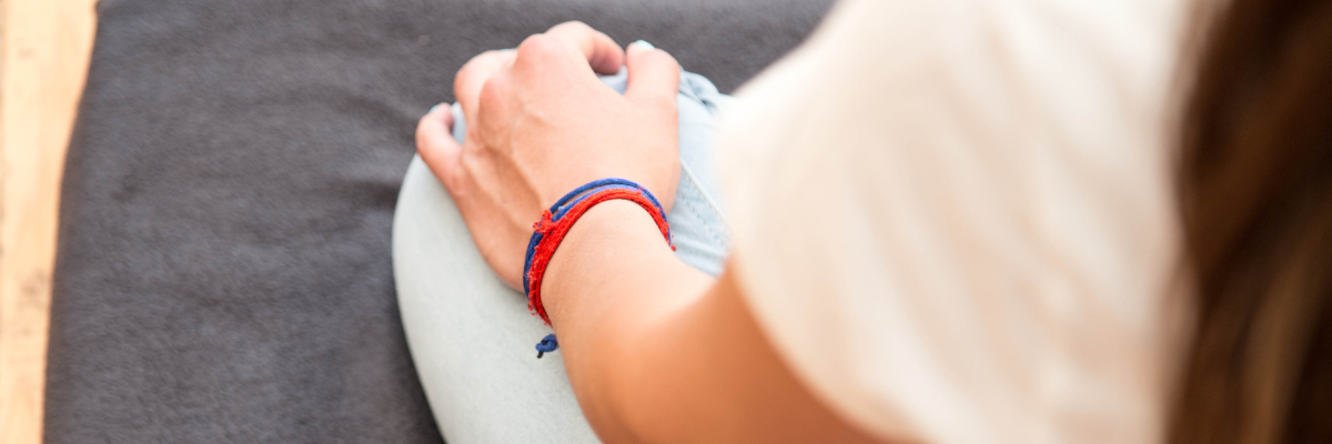 Detailaufnahme einer Hand einer meditierenden Person, die Hand liegt auf dem Knie