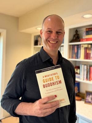Cortland Dahl blickt in die Kamera und hält sein Buch A Meditator's Guide to Buddhism in der Hand.